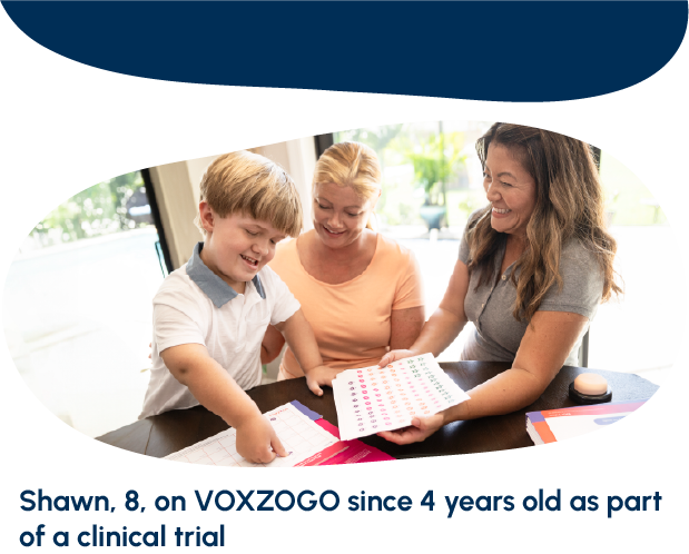 A child and two adults looking at a sheet of paper and smiling